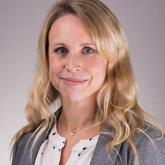 A woman wearing a white shirt with a gold necklace. Description generated by AI